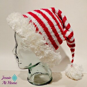 May include: A red and white striped Santa hat with a white fluffy trim and a matching pom-pom at the end. The hat is knit and has a long, pointed shape, perfect for the holiday season.