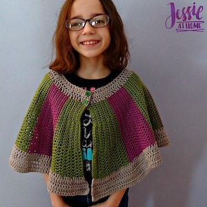 May include: A handmade crochet cape in green, pink, and tan. The cape features a striped design with a button closure. The image includes the text "Jessie at Home".