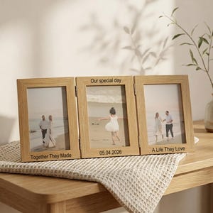 May include: A light wood triple folding picture frame featuring three photos of people on a beach. The frame is engraved with the text Our special day, 05.04.2026, Together They Made, and A Life They Love, displaying three distinct memories.