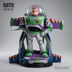 Puede incluir: Una figura de acción de Buzz Lightyear de pie sobre una base con alas extendidas. La figura viste un traje blanco, verde y morado con un casco transparente. El texto dice RATH SPACE y CRAFTED IN SPACE PRINT ON EARTH.