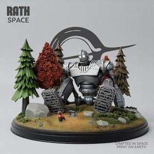 Könnte beinhalten: Eine silberne Roboterfigur mit leuchtend weißen Augen sitzt auf einem runden Sockel, der eine Miniatur-Waldlandschaft mit grünen und orangefarbenen Bäumen, Felsen und einer kleinen Figur zeigt. Der Text RATH SPACE und CRAFTED IN SPACE PRINT ON EARTH ist sichtbar.