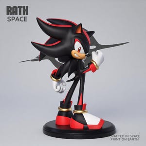Peut inclure: Une figurine de Shadow the Hedgehog debout sur une base circulaire noire. Le personnage est noir avec des accents rouges, des gants blancs et des anneaux dorés aux poignets et aux chevilles. Le texte RATH SPACE et CRAFTED IN SPACE PRINT ON EARTH est visible.