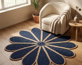 May include: A round, flower-shaped area rug featuring a central point with twelve radiating petals. The rug is constructed from braided fibers, alternating between deep navy blue and natural tan sections, creating a distinct floral pattern.