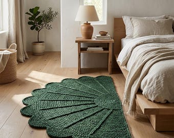 May include: A semi-circular dark green rug with a textured, chunky knit construction. The rug features a radiating fan-like pattern with raised ridges extending from a central semi-circle to a scalloped edge, lying on a light wood floor.