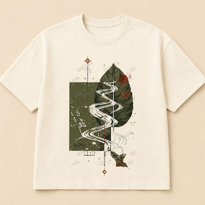 Puede incluir: Una camiseta de manga corta color crema con un diseño gráfico central. El estampado incluye un bloque rectangular verde oscuro, una hoja grande de color verde oscuro y líneas blancas fluidas que parecen un arroyo, con pequeños detalles geométricos rojos.