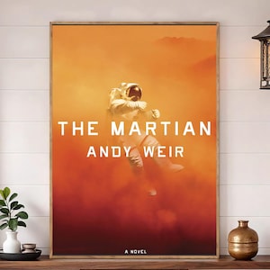 May include: A rectangular poster featuring an astronaut in a white suit floating against a vibrant orange and red dusty background. The text THE MARTIAN ANDY WEIR is printed in white capital letters in the center, with A NOVEL at the bottom.