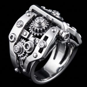 Puede incluir: Un anillo de tono plateado con un diseño mecánico complejo que presenta engranajes expuestos, cabezas de pernos hexagonales y pequeñas piedras redondas transparentes incrustadas en la estructura metálica de estilo industrial.