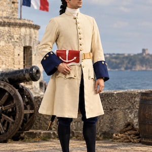 Puede incluir: Un abrigo largo de color beige con puños azules y botones dorados, usado con un sombrero de tres picos negro, una corbata blanca, calzones azul oscuro, medias negras y zapatos con hebilla negros. Una bolsa roja y blanca con un ancla en la cintura.