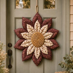May include: A fabric wall hanging shaped like a large flower with two layers of petals. The outer petals are solid dark maroon, while the inner petals are cream with a small maroon floral print. The centre is a circular, textured tan rope coil.