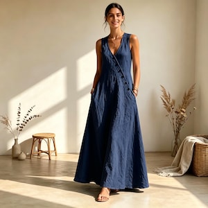 Puede incluir: Un vestido largo azul marino sin mangas con escote en V y una tapeta de botones diagonal en la parte delantera. El vestido tiene una silueta relajada y fluida que llega hasta el suelo, confeccionado en un tejido texturizado con bolsillos laterales.