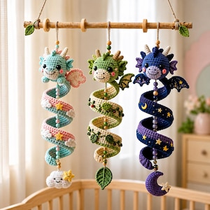 Peut inclure: Trois mobiles dragons en crochet suspendus à une tige en bois. Le dragon de gauche est bleu clair avec une queue en spirale rose et bleue ornée de nuages et d'étoiles. Le dragon central est vert avec une queue à motifs de feuilles. Le dragon de droite est bleu foncé avec une queue en spirale violette et bleue ornée de lunes et d'étoiles.