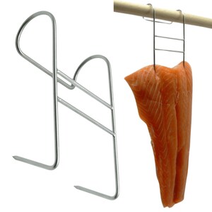 Könnte beinhalten: Ein silberfarbener Fischräucherhaken aus Metall mit zweizinkigem Design und gebogenem Oberteil zum Aufhängen. Der Haken ist sowohl als einzelnes Objekt als auch im Einsatz dargestellt, wobei er ein großes, orangefarbenes Lachsfilet an einem Stab hält.