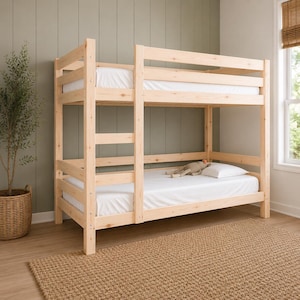 May include: A light-colored natural wood bunk bed featuring a sturdy frame with horizontal slats on both the top and bottom levels. The bed includes white mattresses on both tiers and a small stuffed animal resting on the bottom mattress.