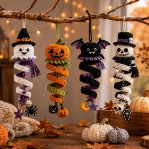 May include: Four hanging crochet ornaments featuring Halloween characters: a ghost in a witch hat, a jack-o'-lantern, a black bat, and a skeleton in a top hat. Each figure has a long, spiralling tail decorated with small charms like stars, spiders, and pumpkins.