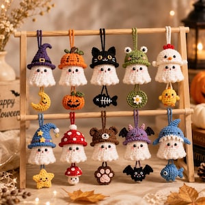 May include: Ten crocheted ghost ornaments hanging on a wooden stand. Each white ghost wears a different hat, including a purple witch hat, orange pumpkin, black cat, green frog, white chicken, blue wizard hat, mushroom, bear, bat, and shark.