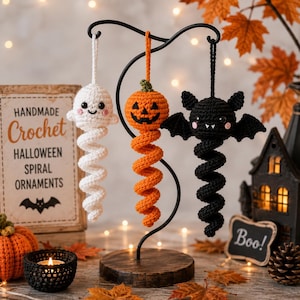 Può includere: Tre decorazioni di Halloween realizzate a mano all'uncinetto appese a un supporto in metallo nero. Il set include un fantasma bianco, una zucca arancione e un pipistrello nero, ognuno con una coda a spirale e un occhiello.