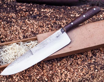 May include: A fixed-blade knife with a silver-colored metal blade featuring a textured, file-like pattern near the spine. The handle is made of dark brown wood and is secured with three small, circular silver-colored rivets along the side.