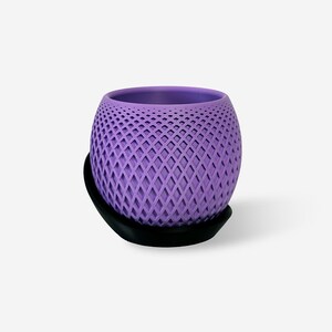 May include: A spherical lavender planter featuring a textured diamond lattice pattern across its exterior surface. The planter is securely seated within a solid black circular base that provides a stable foundation for the rounded vessel.