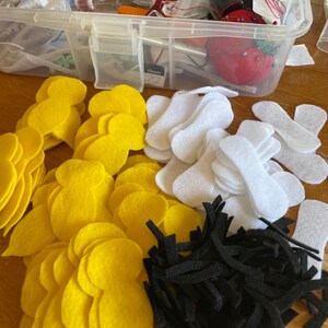 May include: A collection of felt craft supplies including yellow, white, and black felt pieces. The felt pieces are in various shapes and sizes.