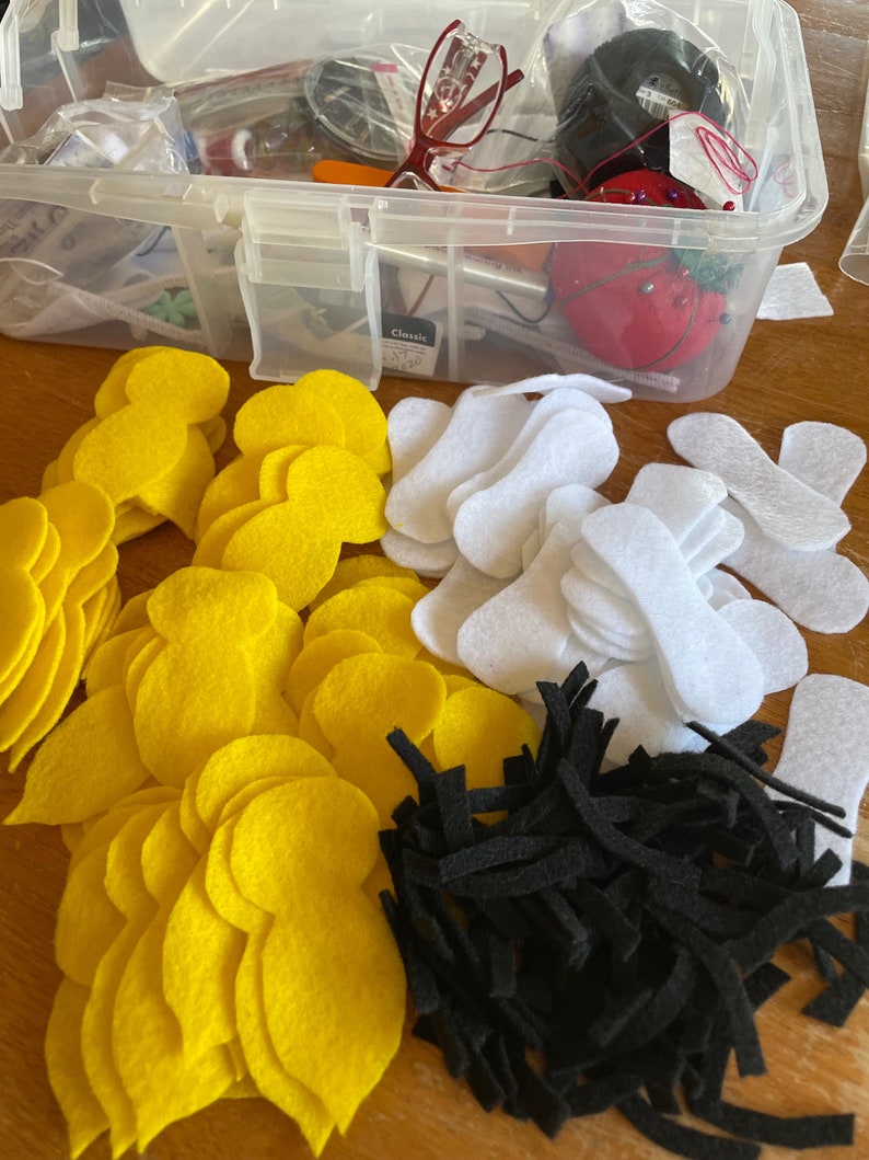 May include: A collection of felt craft supplies including yellow, white, and black felt pieces. The felt pieces are in various shapes and sizes.