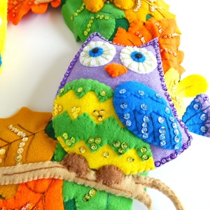 May include: A purple felt owl with green, yellow, and blue felt accents. The owl is decorated with iridescent sequins and has a felt branch attached to its body.