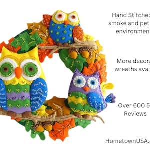 May include: A colorful felt owl wreath with three owls, one yellow, one blue, and one purple, with sequins and beads. The wreath is decorated with felt leaves in shades of orange, yellow, and green. The text "HometownUSA.etsy" is visible in the bottom right corner.
