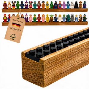 Può includere: Due lunghi ripiani in legno con strisce di mattoncini in plastica nera sulla parte superiore, ognuno dei quali sostiene una fila di variopinte statuette in plastica. Un cartellino in cartone beige riporta il testo DESIGNED IN GERMANY.