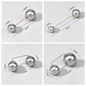 Könnte beinhalten: Vier silberfarbene Metallnadeln mit jeweils zwei kugelförmigen grauen Kunstperlen an den Enden. Die Nadeln variieren in der Länge von 4,9 cm bis 7,0 cm, mit Perlendurchmessern von 1,2 cm und 1,6 cm, wie durch die sichtbaren Maßangaben belegt.