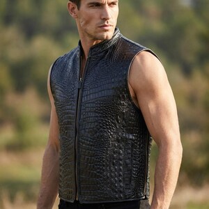 May include: A sleeveless black vest featuring a textured crocodile skin pattern. The garment has a high collar, a full-length front zipper closure, and vertical side pockets. The material has a glossy finish and a structured, fitted silhouette.