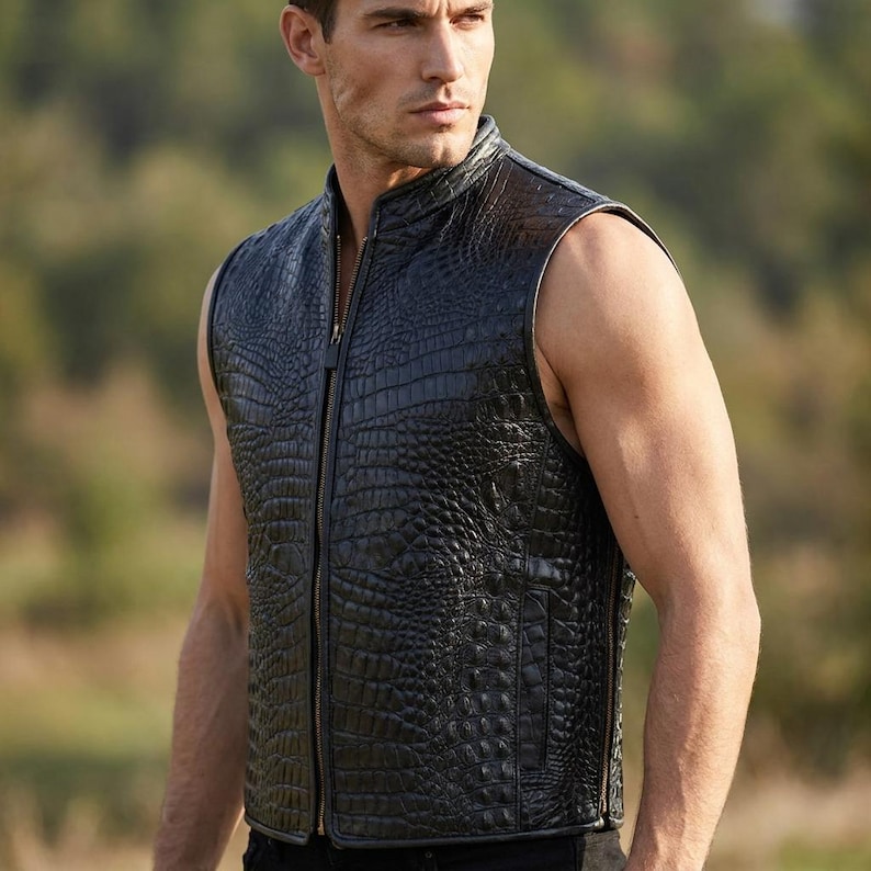 May include: A sleeveless black vest featuring a textured crocodile skin pattern. The garment has a high collar, a full-length front zipper closure, and vertical side pockets. The material has a glossy finish and a structured, fitted silhouette.