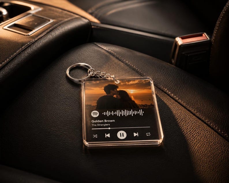 May include: A square clear acrylic keyring featuring a printed photograph of a couple at sunset, a Spotify-style waveform, and the text Golden Brown by The Stranglers, complete with playback control icons and a silver metal split ring attachment.