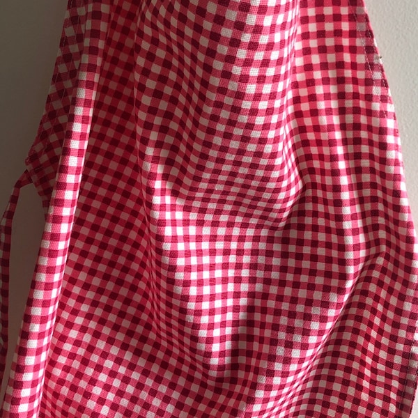 Le tablier vichy surpiqué pour enfant dans les tons de rose et de rouge mesure 21" de long sur 17" de large.