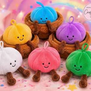 May include: Six plush pumpkin-shaped toys with smiling faces, each featuring brown legs and a small loop on top. The pumpkins are coloured white, yellow, blue, pink, purple, and green. Some sit inside brown plush baskets. Text reads: PERSONALISED Crafts KP.