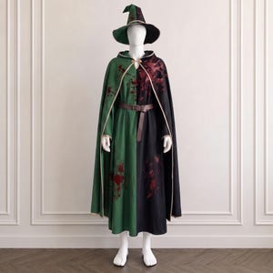 May include: A split-color cloak and matching pointed hat featuring a green side and a black side. The garment is accented with dark red splatter patterns, a brown leather-look belt at the waist, and a metallic clasp at the neck closure.