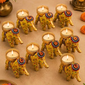 Peut inclure: Un ensemble de huit bougeoirs en forme d'éléphant jaune, chacun orné d'un motif floral, d'un accent circulaire coloré au cou et d'une coupelle en maille métallique dorée contenant une bougie chauffe-plat blanche allumée.