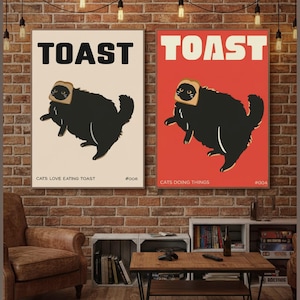 Könnte beinhalten: Zwei rechteckige Wandposter mit einer schwarzen Katze, die eine Scheibe Toast auf dem Kopf trägt. Das linke Poster hat einen cremefarbenen Hintergrund mit dem Text TOAST, CATS LOVE EATING TOAST und #006. Das rechte Poster hat einen roten Hintergrund mit dem Text TOAST, CATS DOING THINGS und #004.