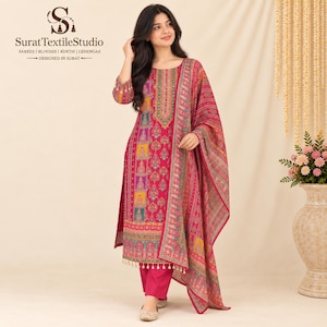 May include: A vibrant fuchsia long-sleeved kurta featuring a multi-colored geometric and floral print, paired with matching solid fuchsia trousers and a coordinating printed dupatta with tassel trim. The garment displays the SuratTextileStudio logo.