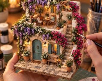 May include: A miniature two-story Mediterranean-style house model featuring a teal arched door, stone-textured walls, and a stone-paved patio. The structure is adorned with cascading purple wisteria and vibrant pink bougainvillea flowers.