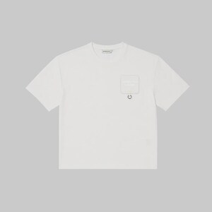 May include: A short-sleeved white t-shirt featuring a crew neckline and a square patch pocket on the left chest. The pocket includes a small metal ring attached at the bottom edge and subtle text printed on the surface of the pocket fabric.