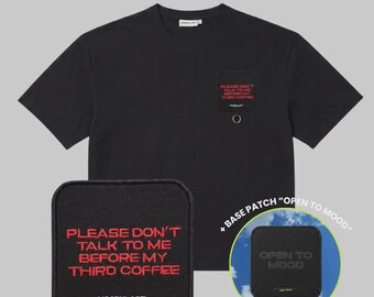 May include: A black short-sleeve t-shirt featuring a square patch on the chest with the red text "PLEASE DON'T TALK TO ME BEFORE MY THIRD COFFEE" and a metal ring. Includes an additional patch with the text "OPEN TO MOOD" on a blue sky background.