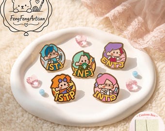 May include: Five circular enamel pins featuring cartoon characters representing personality types ISTJ, INFJ, ENTJ, ISTP, and INTP. Each pin displays a character with distinct hair color and accessories, with the four-letter acronym in bold gold lettering.