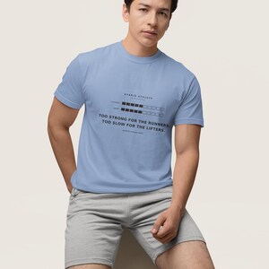 May include: A light blue short-sleeved t-shirt featuring a black graphic print that reads HYBRID ATHLETE, includes two progress bars for strength and speed, and the text TOO STRONG FOR THE RUNNERS, TOO SLOW FOR THE LIFTERS.