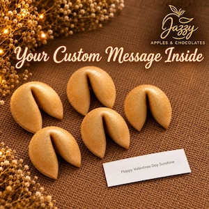 May include: Four golden-brown fortune cookies arranged on a textured brown surface. A white paper strip lies nearby with the printed text Happy Valentines Day Sunshine. The logo Jazzy Apples & Chocolates and the text Your Custom Message Inside.