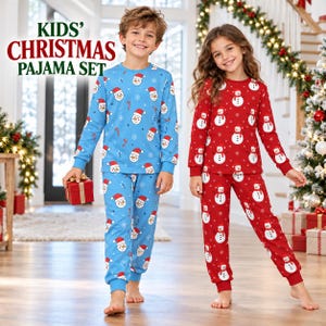 Può includere: Set pigiama a due pezzi per bambini con motivo a pupazzi di neve e fiocchi di neve. Un set è blu con pupazzi di neve con cappello rosso, l'altro è rosso con pupazzi bianchi. Il testo KIDS' CHRISTMAS PAJAMA SET è visibile in alto a sinistra.