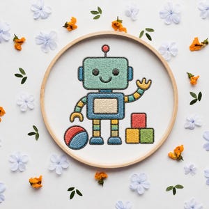 May include: A circular wooden embroidery hoop frames a white fabric piece featuring a stitched design of a light blue robot with a red antenna, a yellow and blue striped arm, and a smiling face. The robot stands beside a red ball and three blocks.