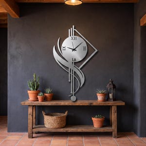 K&ouml;nnte beinhalten: Eine silberfarbene Wanduhr aus Metall mit einem runden Zifferblatt, schwarzen r&ouml;mischen Ziffern und d&uuml;nnen schwarzen Zeigern. Die Uhr ist in einen geometrischen Rahmen mit vertikalen Linien, einer rautenf&ouml;rmigen Kontur und einem geschwungenen Akzent integriert.