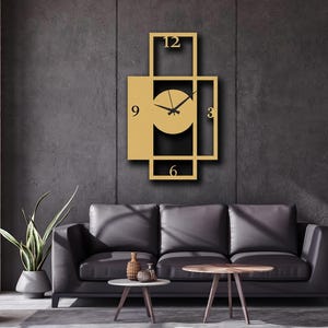 Pu&ograve; includere: Un orologio da parete rettangolare con una cornice in metallo dorato dal design geometrico aperto. Il quadrante &egrave; circolare con lancette nere e i numeri neri 3, 6, 9 e 12 posizionati ai punti cardinali della struttura della cornice.