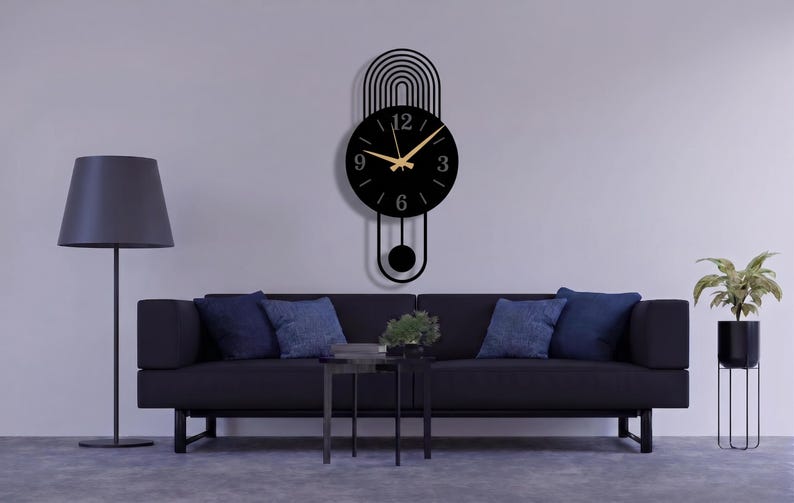 May include: A black wall clock with a circular face, gold-colored hands, and numerals at the 3, 6, 9, and 12 positions. The clock features a decorative arched top design with vertical lines and a pendulum component extending below the main dial.