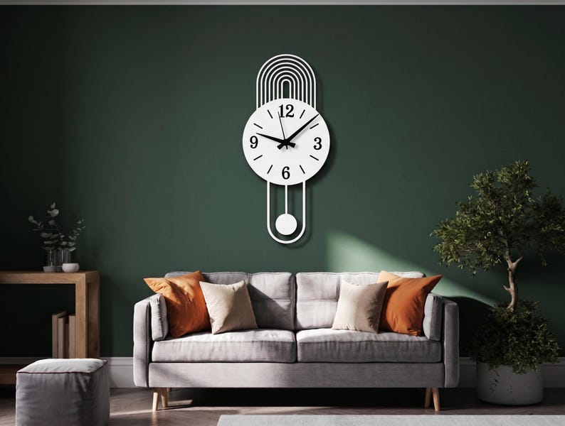 May include: A white wall clock featuring a circular face with black numerals at the 3, 6, 9, and 12 positions, black hour and minute hands, a thin black second hand, an arched top design, and a pendulum with a circular weight at the bottom.