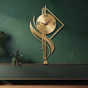 K&ouml;nnte beinhalten: Eine goldfarbene Wanduhr mit einem runden Zifferblatt, schwarzen r&ouml;mischen Ziffern und d&uuml;nnen schwarzen Zeigern. Die Uhr ist in einen dekorativen Metallrahmen mit l&auml;nglichen vertikalen Linien und geschwungenen, blattartigen Formen integriert.